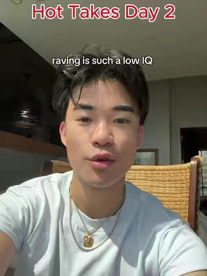 A young man is shown from the chest up, centered in the frame. The image is well-lit, highlighting the man’s face and upper body. He has short, dark hair and fair skin. He is wearing a light blue t-shirt and a gold chain with a pendant. A text overlay at the top reads "Hot Takes Day 2" in red.
