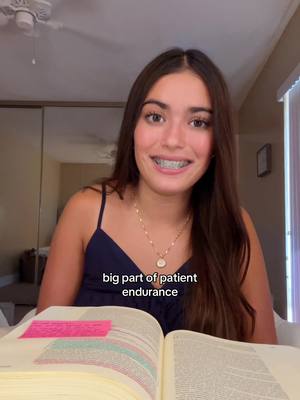 A young woman with long brown hair and braces is seated in front of an open book, a pink sticky note is attached to one of the pages. Text overlay says 'big part of patient endurance'.  She is wearing a navy blue top and a gold necklace. The background includes a mirror, part of a ceiling fan, and a window.