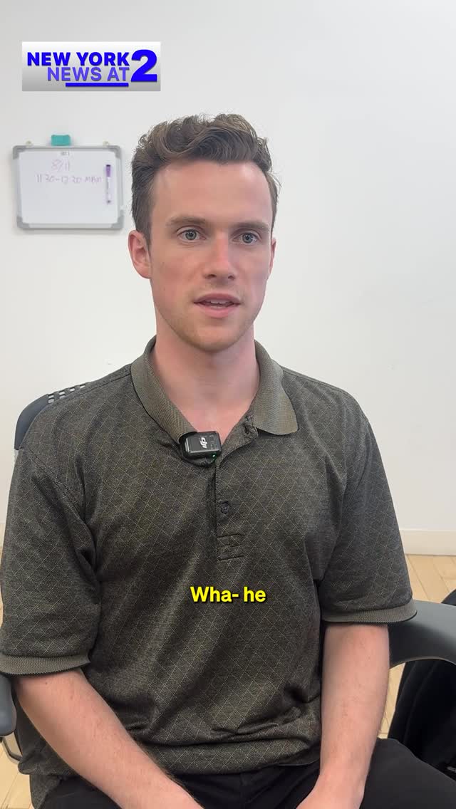 A man with fair skin and short brown hair is centered in the frame, looking slightly upward. He's wearing a dark green polo shirt. Above him, there is a logo that says New York News at 2 . Below the man, the yellow text overlay reads "Wha- he".