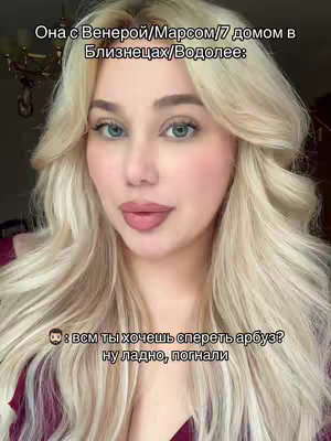 A close-up shot of a blonde woman with blue eyes and full lips, looking directly at the camera. Text overlays are positioned at the top and bottom, detailing astrological aspects and a playful question. The lighting appears soft and natural, highlighting her features. The background is out of focus but hints at an indoor setting.