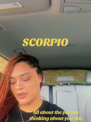 A woman with red braided hair is sitting in a car, looking into the camera. Yellow text at the top says "SCORPIO". Text at the bottom says "All about the person thinking about you this". The car interior is visible.