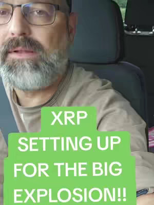 A man with glasses and a beard is shown from the chest up, inside a car. A large green shape displays the text 'XRP SETTING UP FOR THE BIG EXPLOSION!!'. The car's headrest is visible in the background.