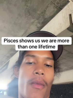 A selfie-style video cover image shows a person with long dark hair and a mustache wearing a baseball cap. The background is a concrete ceiling. Text overlay reads, 'Pisces shows us we are more than one lifetime'.