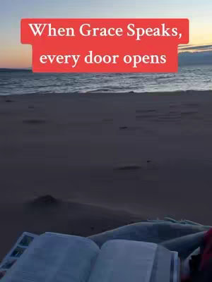 The cover image shows a serene beach scene at dawn or dusk. The sky transitions from orange to pale blue above the ocean, with the water reflecting the colors of the sky. In the foreground, a dark sandy beach leads to the viewer's eye. An open book, possibly a Bible, rests on the sand, its pages visible. A red text box overlays the image, containing a message.