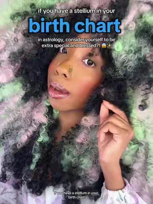 A selfie-style image. A person with colorful curly hair and makeup gazes at the camera with opened lips and a finger close to their face. Text overlays at the top and bottom highlight the focus on birth charts and astrology.