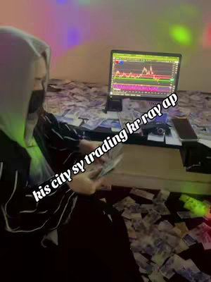 A person in a hoodie and a mask is seated with a laptop open, surrounded by a large amount of money. The setting is a room with colorful lights. The laptop screen displays what appears to be financial trading data.