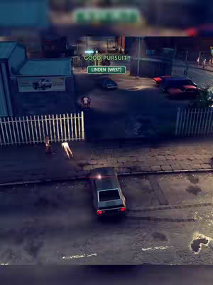 An overhead view of a video game scene set at night. The scene depicts a car at the bottom of the frame, with police tape and two figures near a white fence on the left. In the middle distance, a car is parked, and there are buildings and signs with some text. The lighting gives a dramatic effect, with a green banner at the top of the image.