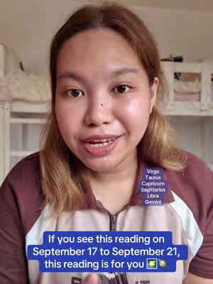 A woman with light skin and brown hair is centered in the frame, directly facing the camera. Text overlays are present, including a list of zodiac signs and an announcement about the video's relevance during a specific time frame. The overall composition is a close-up view, with the background softly blurred and out of focus, and a woman is wearing a maroon top. The lighting appears to be soft and natural.