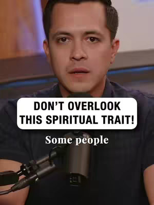 A man with short dark hair and a dark blue shirt is looking slightly off-camera. Overlayed on the image are two text boxes, one with the text 'DON'T OVERLOOK THIS SPIRITUAL TRAIT!' and another with 'Some people'. In front of the man is a black microphone angled towards his face.