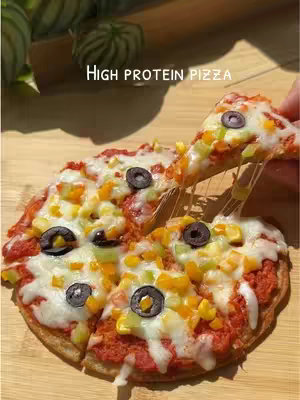 The cover image showcases a sliced pizza with melted cheese and toppings. The pizza rests on a wooden surface, with an additional slice being lifted. The background features some green leaves and is well lit.