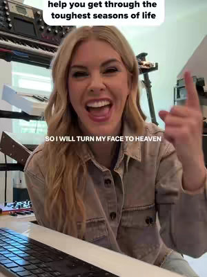 A woman with blonde hair is smiling and pointing upwards with her right hand. Text overlays are at the top and bottom.