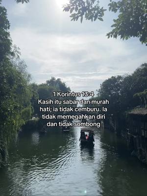 An eye-level shot captures a serene river scene. The water, a muted green, reflects the sky and surrounding trees. Two small boats, each carrying passengers, navigate the river. Lush greenery lines the banks, and the soft, overcast sky fills the upper portion of the frame. Text is overlaid on the upper right, and the aesthetic is calm, natural, and contemplative.