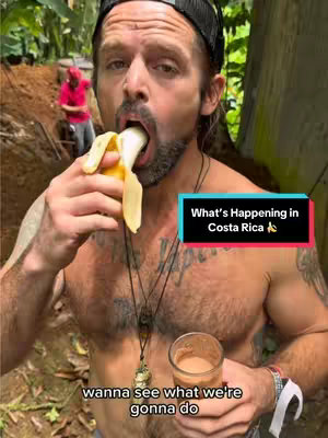 A shirtless man is seen biting into a banana and holding a glass in one hand. A text overlay at the bottom reads, 'wanna see what we're gonna do'. In the background, a person wearing a red t-shirt and a hat works in a dirt area.