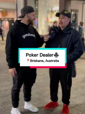 Two men are standing outdoors in a city setting, engaged in an interview. The man on the left wears a black hoodie and a black cap, while the man on the right is wearing a black jacket and a black cap, holding a microphone, interviewing the other. A text overlay reading 'Poker Dealer', along with a card suit symbol and location details.