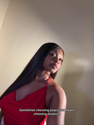 A woman with long black hair and a red dress is centered in the well-lit shot. The image is vertically oriented and has a blurred background, with some visible wall details. Text is added on the bottom, reading: 'Sometimes choosing peace just means choosing distance.'
