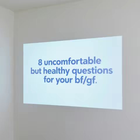 A light-colored wall with a rectangular projection displaying text. The text is in a friendly font and reads "8 uncomfortable but healthy questions for your bf/gf."
