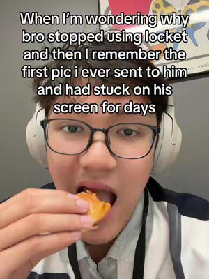 A close-up selfie of a young person wearing glasses and headphones is eating a pastry. The person is holding a part of the food up to their mouth, with a slightly open mouth. Behind them is a blurred background.