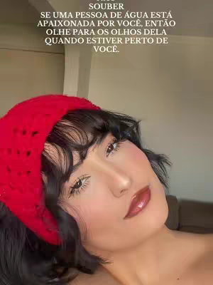 A young woman with dark hair and red headband looks at the camera. The background is nondescript, and the overall tone of the image is intimate. The woman is wearing makeup with visible blush and lip color.