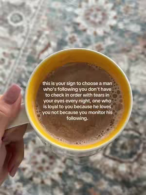 The image presents a close-up view of a mug filled with a warm, brown beverage, likely hot chocolate or coffee. The mug has a yellow interior and sits atop a patterned surface, possibly a rug or a blanket, which provides a textured background. The rim of the mug is visible, and the liquid's surface is slightly foamy. The text overlays the image.