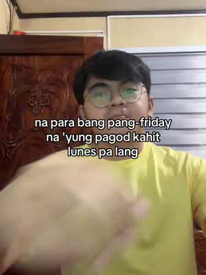 A young man with glasses is centered in the frame, wearing a yellow shirt. His right forearm extends into the shot. Text overlayed on the image reads in Tagalog about feeling tired like it's Friday despite it being Monday.