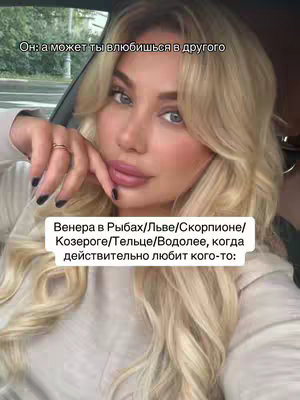 A selfie-style shot of a young woman seated in a vehicle, with her face and upper body in clear view. She has blonde hair styled and has makeup applied, including subtly defined lips and eye makeup. The background is soft, suggesting the inside of a car with a glimpse of the exterior. Overlaid text in a rectangular box provides additional context or information about the video's topic.