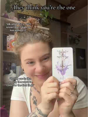 A woman with curly hair holds a tarot card, smiling at the camera. Text overlays read, 'They think you're the one' and quotes attributed to a reading, with a bookshelf visible in the background.