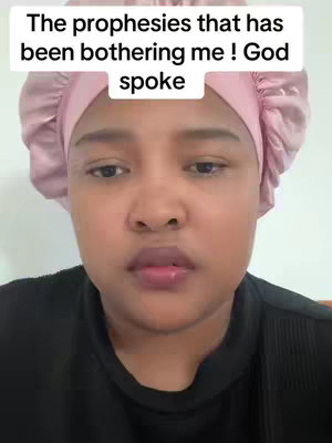 A selfie-style video showing a person with brown skin and a light pink head covering. The person is looking slightly up, with a neutral expression. Overlay text in a white box at the top of the image says 'The prophesies that has been bothering me! God spoke'.