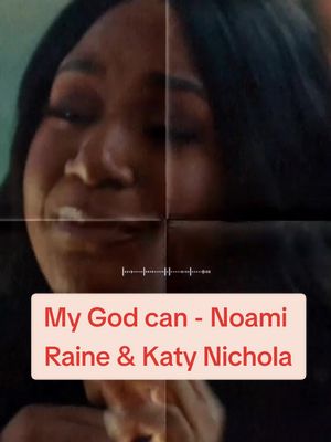 The image is a close-up on a woman's face. She has dark hair and is looking down, likely with her eyes closed. A text bar at the bottom reads "My God can - Noami Raine & Katy Nichola" in a red and white color scheme.