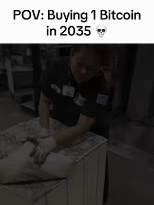 A person in a dark uniform, wearing safety glasses and gloves, is working with a large bale or package, presumably of something like money, in a warehouse setting. The person handles the bale with care. Text overlays at the top indicate the scene relates to bitcoin in 2035, playing on the idea that it will be very expensive.