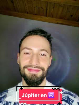 A medium shot featuring a man with a beard smiling at the camera. A text overlay at the bottom of the screen that reads Júpiter en.