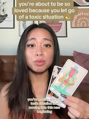 A woman with long dark hair is holding up two tarot cards in front of her. The background shows a living room setting with framed artwork. Text overlays are present at the top and bottom of the frame.