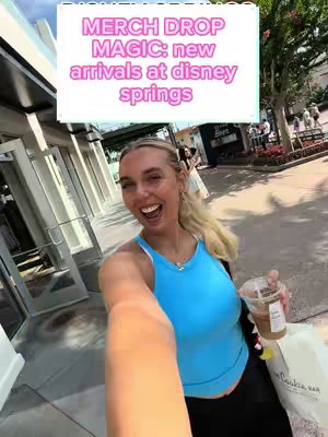A woman is taking a selfie in front of what appears to be a Disney Springs store, holding a drink and shopping bag. Overlay text reads 'MERCH DROP MAGIC: new arrivals at disney springs'. The woman is smiling with open mouth and fair hair.