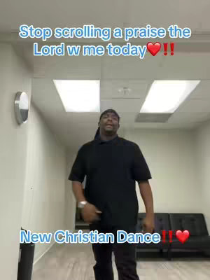 The video shows a man dancing in a room with a black shirt and pants. Above the man, there is text overlay. At the bottom, there's also some text. The lighting seems to be from overhead lights, and there are some black benches visible in the background.