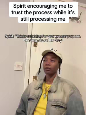 A person with light skin and dark braids is wearing a white cap, gold necklace and a yellow shirt under a neutral colored jacket. The image has text boxes overlaid in the top and bottom of the image with a quote from the spirit in the bottom text box.
