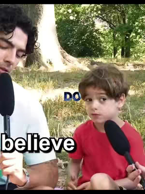 The cover image shows two people holding microphones outdoors. The person on the left, an adult male with dark curly hair, is holding a microphone near his face. Adjacent and to the right is a young boy with brown hair, looking at the camera with a slightly concerned expression, holding a microphone. Text overlays read "believe" and "DO". The background is a blurred green landscape.