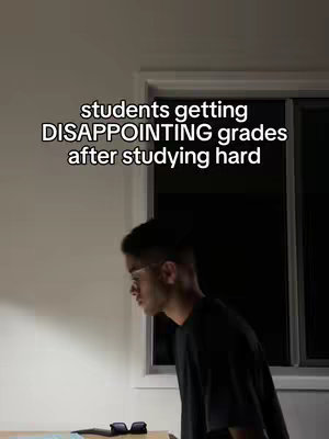 A young man in glasses, wearing a black t-shirt, stands in front of a window looking down, seemingly dejected. The overlay text reads: "students getting DISAPPOINTING grades after studying hard". The room appears to be lit by daylight, and a pair of black glasses lies on a desk in the foreground.