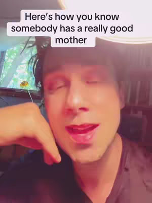 The cover image is a selfie-style shot of a man with rosy cheeks and red lipstick on. His eyes are closed, and he's mid-sentence. Above him, text overlayed that reads, 'Here's how you know somebody has a really good mother'. The background is softly lit, showing glimpses of a room.
