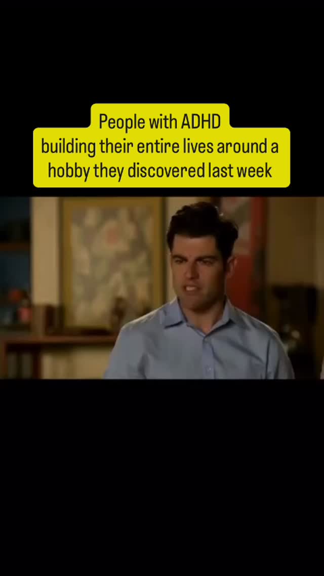 The cover image shows a still from a TV show or movie. The image is framed in a vertical format and features a man with dark hair and a blue button-down shirt in front of a blurry background of an interior setting. Above the man's head, a yellow rectangular banner overlays the scene. The text on the banner reads "People with ADHD building their entire lives around a hobby they discovered last week." The man's expression suggests he's in the middle of a statement or reaction of surprise or contemplation, capturing a relatable experience.