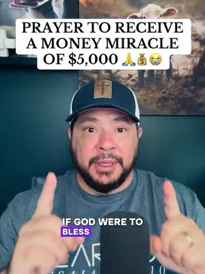 A man with a beard and baseball cap is centered in the frame. The image is a selfie style, with the man's hands raised, index fingers pointing upwards. Text overlays at the top and bottom detail the content's focus on prayer and money miracles. The background is a teal wall with framed artwork.