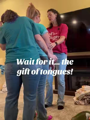 The cover image shows a medium shot of a group of people gathered in a room. Three people are in the foreground, with the person closest to the camera wearing a teal T-shirt, and two others are wearing green t-shirts. Behind them, a woman in a red shirt gestures with her hands. The text overlay says 'Wait for it... the gift of tongues!'