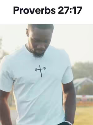 A man wearing a white t-shirt with a cross and barbell symbol, looking down. Text "Proverbs 27:17" is at the top. The background suggests an outdoor setting with sunlight and some blurred natural elements.