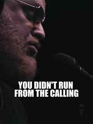 The image presents a close-up shot of a man wearing sunglasses and holding a microphone. He is positioned slightly off-center against a dark background. Overlaid in large, bold, white text is the phrase, "YOU DIDN'T RUN FROM THE CALLING."