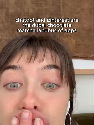 A close-up shot features a person's face, with wide eyes and the fingers of one hand covering their mouth. The background is blurred and features a neutral tone.