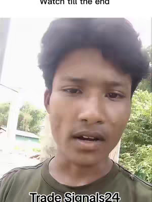 A young man is centered in a video, looking at the camera with a serious expression. The background shows a blurry outdoor scene with trees and foliage. Text overlays at the top and bottom add context.