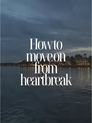 The cover image shows a serene landscape at dusk. A calm body of water reflects the evening sky, with city lights visible on the distant shore. Overlaid on this background is white text stating 'How to move on from heartbreak'. The overall composition creates a tranquil and reflective mood.