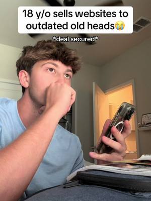 A young man in a light-blue shirt is holding a phone in his right hand. In the background are a blurry bedroom scene and a white door. The cover image has overlaid text that says '18 y/o sells websites to outdated old heads' with a crying-laughing emoji. Below, there is an asterisk-denoted message that states,'deal secured'.