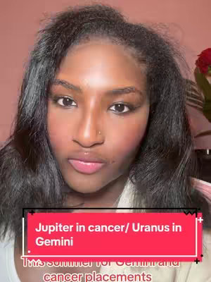 A close-up shot features a young Black woman with long, dark hair and a neutral expression. She gazes directly at the viewer. The background appears to be a light, solid color, possibly a blush or light brown. A red and pink rectangular graphic with overlaying text is placed at the bottom. A small amount of a red floral arrangement is visible in the right side.