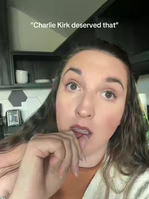 A woman with dark hair and fair skin is shown in a selfie-style shot, with the upper torso and face in sharp focus. She has slightly parted lips and has her finger in her mouth. The background appears to be a kitchen or living area with cabinets and appliances out of focus. The hook is superimposed on the top of the screen.