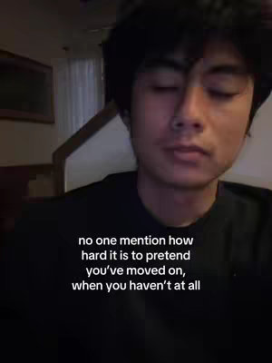 A slightly out-of-focus, medium shot featuring a young man with dark hair looking down with his eyes closed. The text overlayed on the image is a quote about pretending to move on.