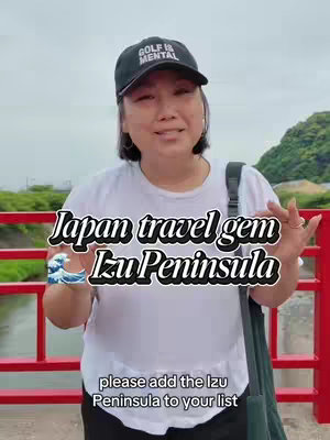 A woman wearing a black cap and white shirt is standing on a red bridge with a river in the background. Text overlays include the video title and a call-to-action. The image has natural lighting, and the composition is centered on the woman and the text.